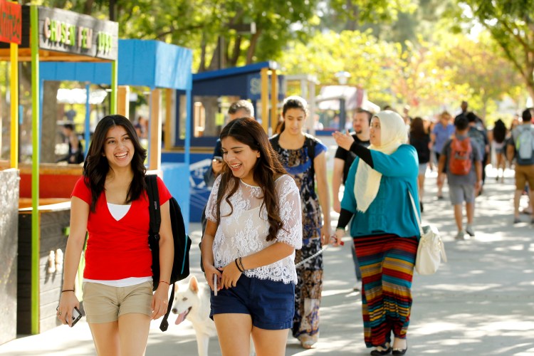 Two young female students laugh as they pass the Student Union building.