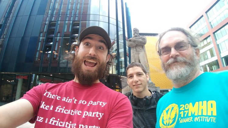 Zach Metzler, Trevor Driscoll and Dr. Chris Golston in front of a statue of Friedrich Engels in Manchester, England.