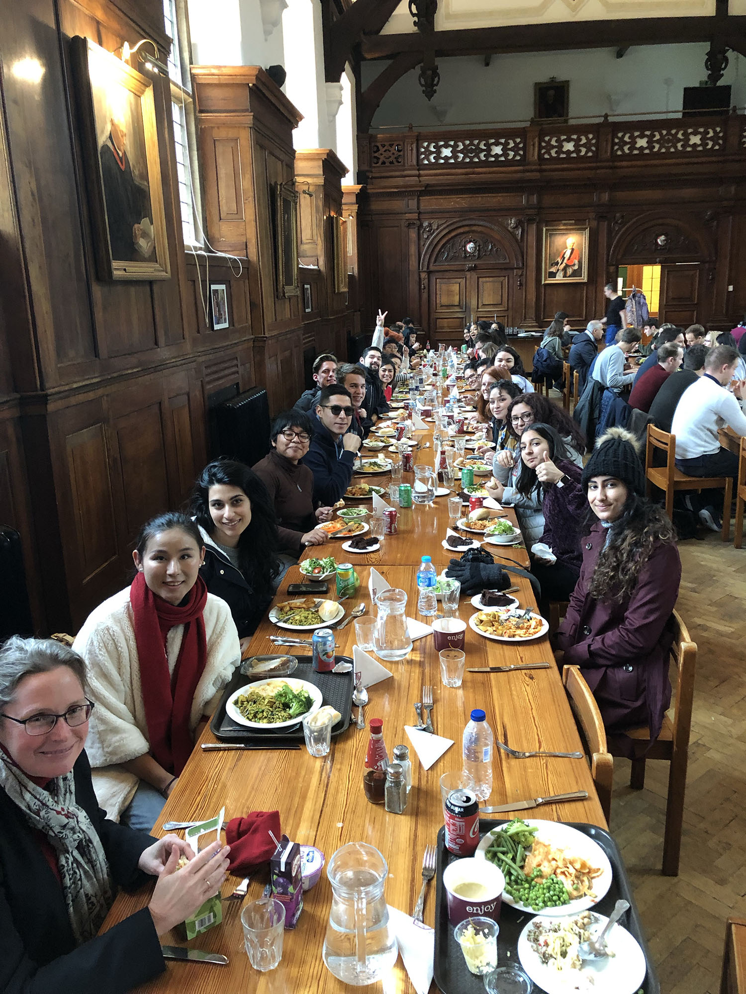 Fresno State students sit for lunch in the Selwyn College Cambridge Dining hall with Sarah MacDonald (bottom left) organist and choirmaster at Selwyn College.