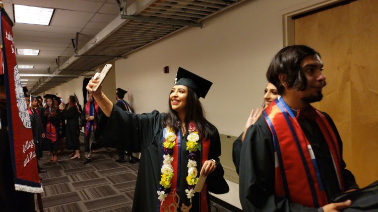 Students take selfies as they line up for CAH Convocation.