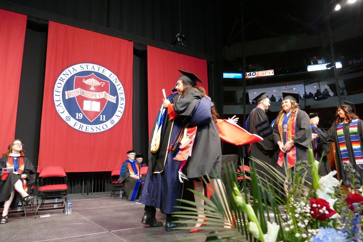 A big hug from Dean Saúl Jiménez-Sandoval as Dean's Medalist Primavera Leal Martinez receives her Bachelor of Arts in English. Martinez was later awarded the President's Medal during Commencement.