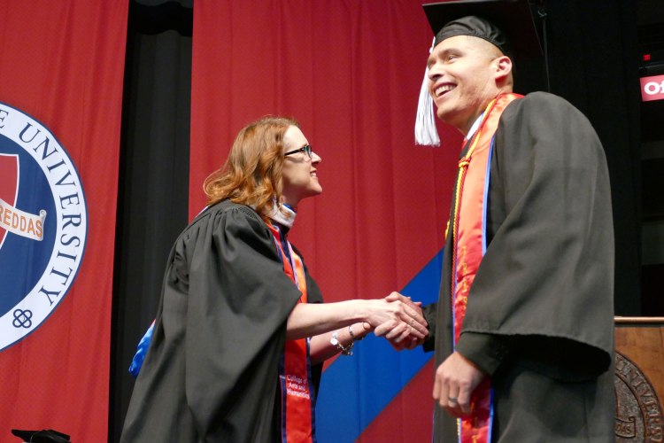 Department of Media, Communications and Journalism chair, Betsy Hays, congratulates Standard Bearer George Garnica.