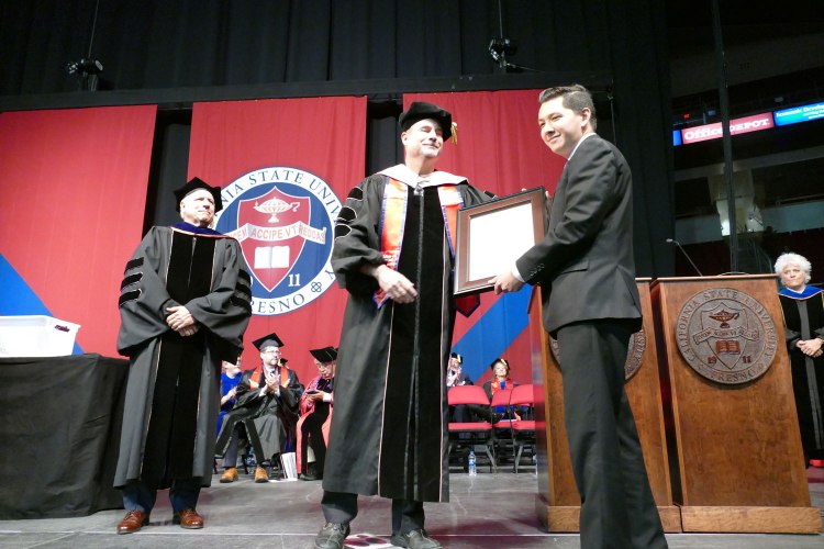 Evan Hamada accepts his father's Bachelor of Science degree Special Major: Music Management posthumously for his father Brian T. Hamada.