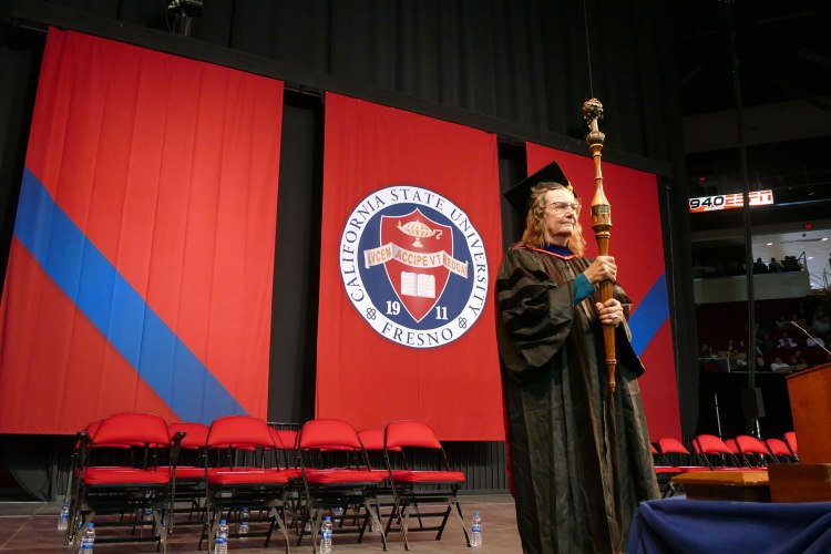 Bearing Fresno State’s ceremonial mace, Chris Henson leads the faculty procession into the Save Mart Center for the University’s 108th Commencement.