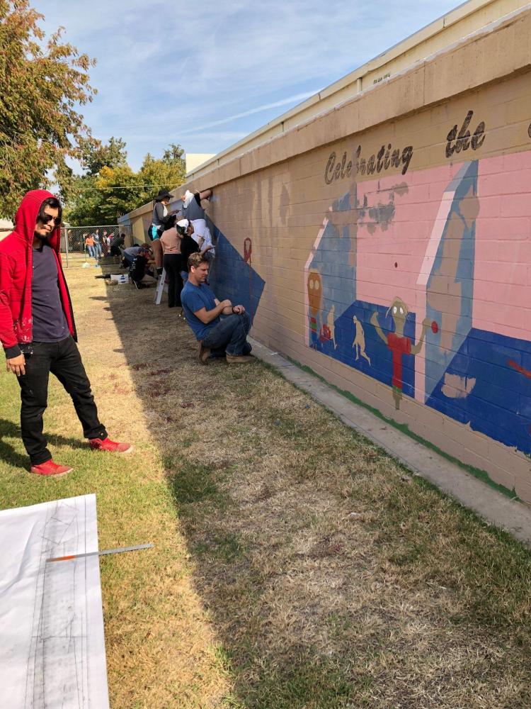 Students and volunteers work on the mural