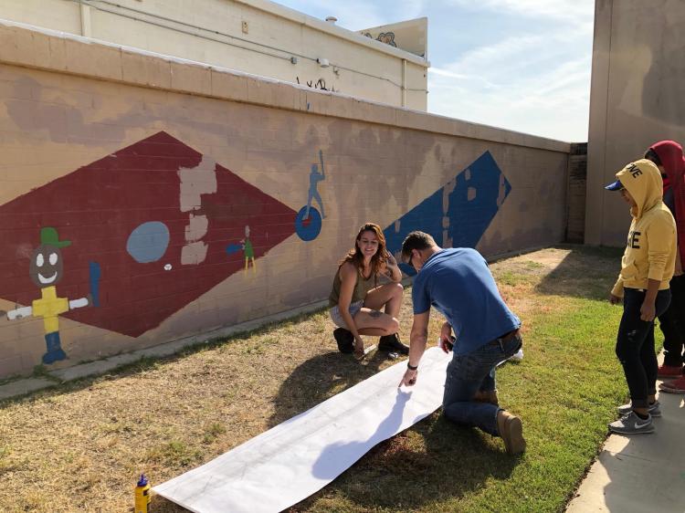 Students and volunteers work on the mural