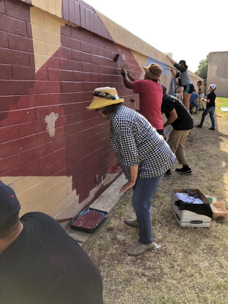 Students and volunteers work on the mural