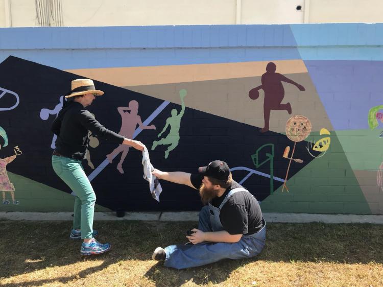Students and volunteers work on the mural