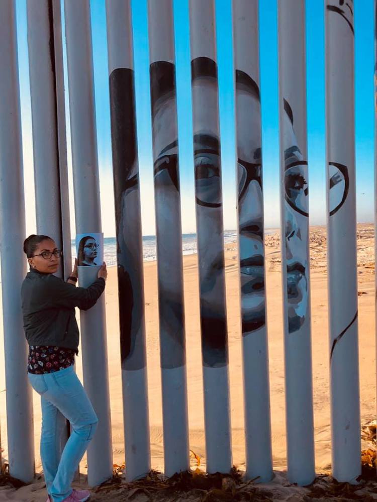Tania stands by her image on the border wall.