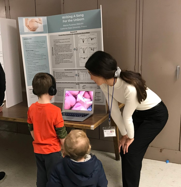 Marina Malcolm with two kids in front of her presentation