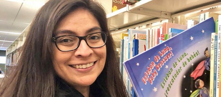 Larissa Mercado-López holds her book "Esteban de Luna, Baby Rescuer! / Esteban de Luna, ¡Rescatador de bebés!"