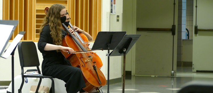 Amid COVID-19, Emma Hill plays the cello durning a live rehearsal in the band practice room.