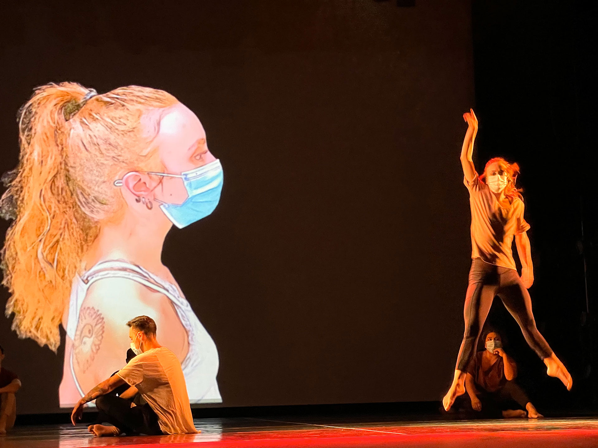Solo dancer performs while large image of herself projected on the back of the stage looks over her.