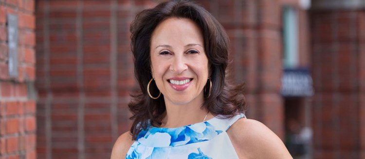Maria Hinojosa in front of a brick building