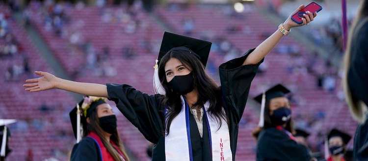 Interior Design graduate throws her arms wide during commencement at Bulldog Stadium.