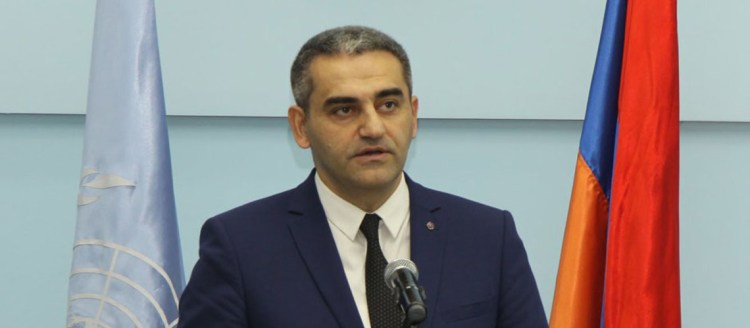 Dr. Suren Manukyan speaks next to the Armenian flag