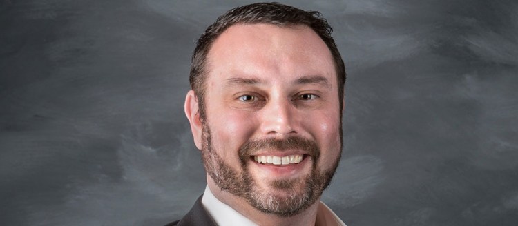 Brian Domingos poses with a grey backdrop.