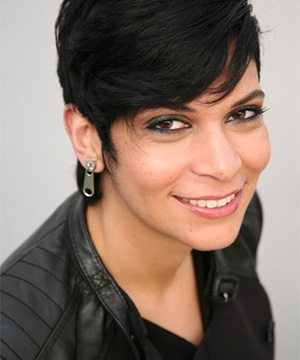 Headshot of Nassem Miller with a black leather top and zipper catch earrings.
