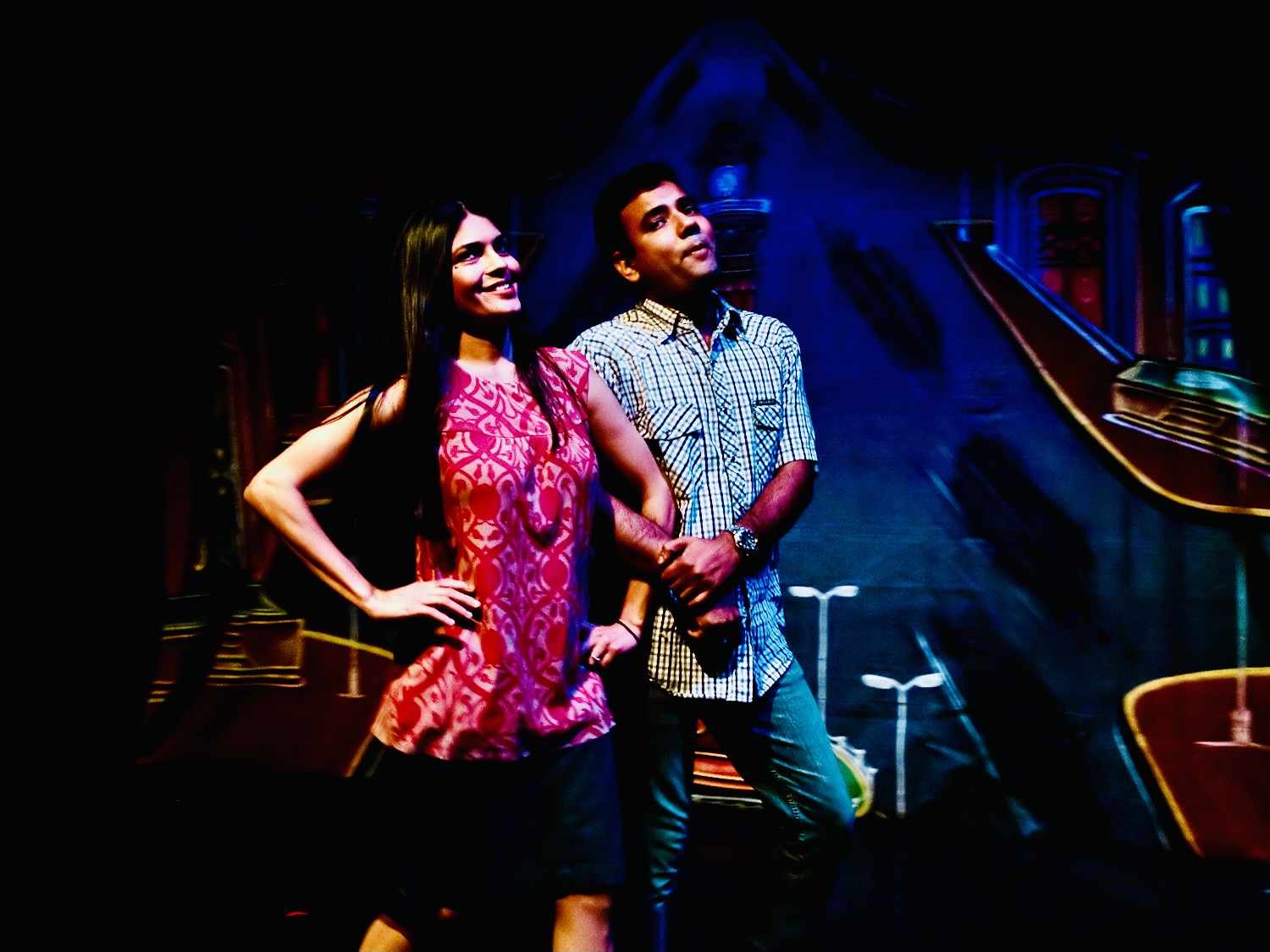 Dr. Devendra Sharma and a fellow performer lock arms in as if on a date in contemporary clothing.