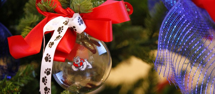Christmas ornament with Fresno State Bulldog logo hangs from a Christmas tree.