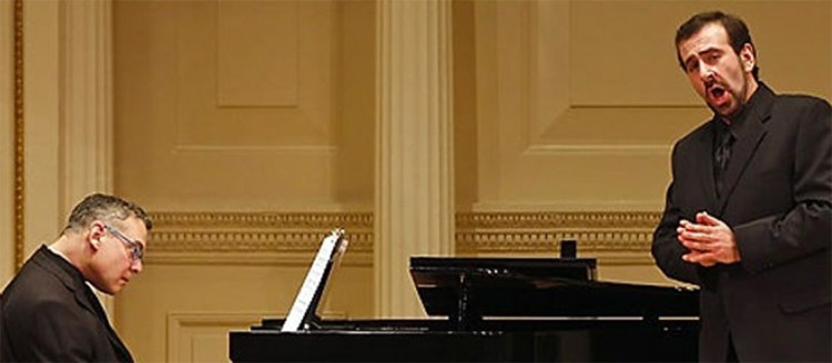 Dr. Anton Belov sings in front of a grand piano.