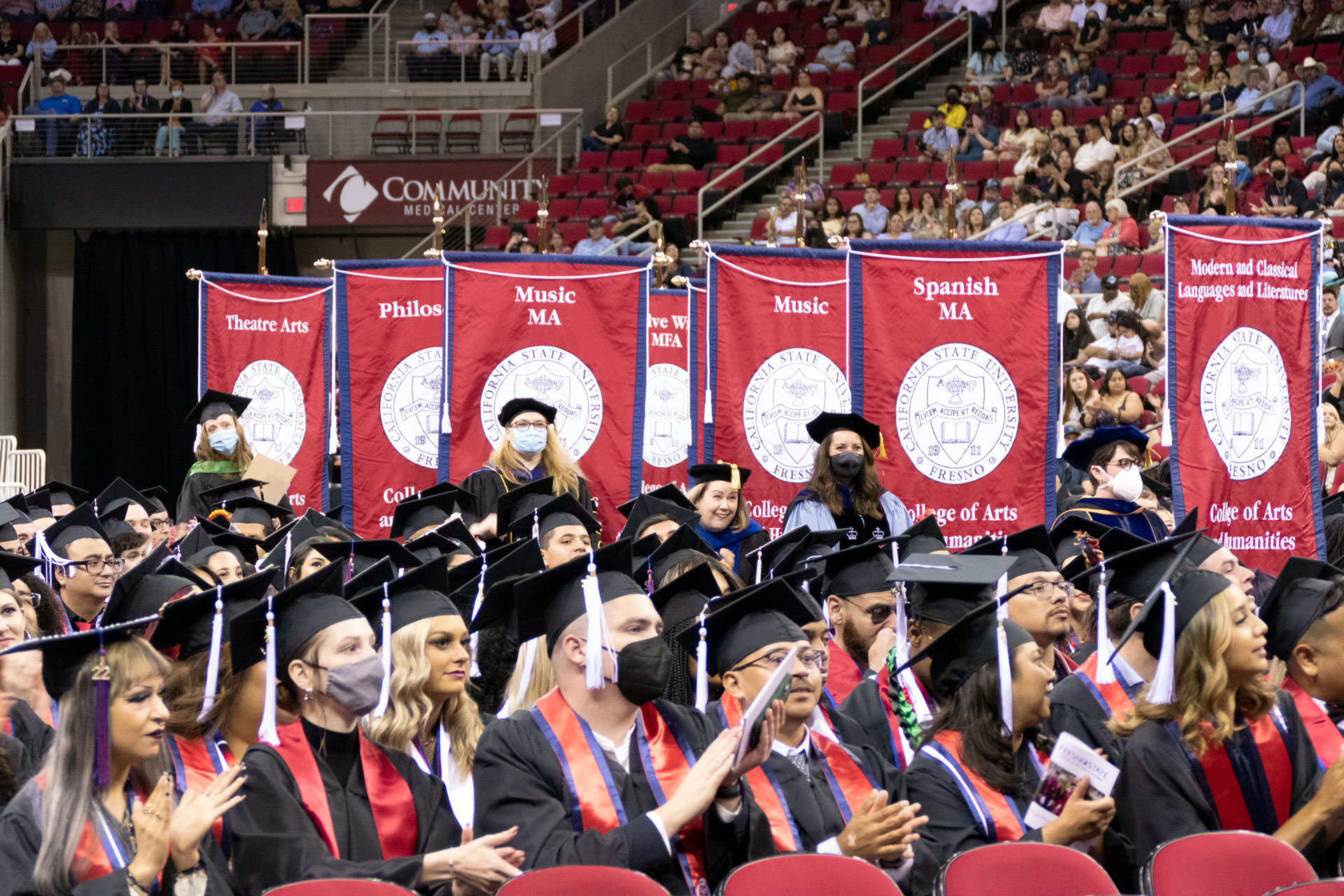 Students seated as faculty carry banners of each department.