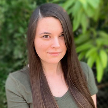 AnnMarie Kornele in front of green trees and plants.