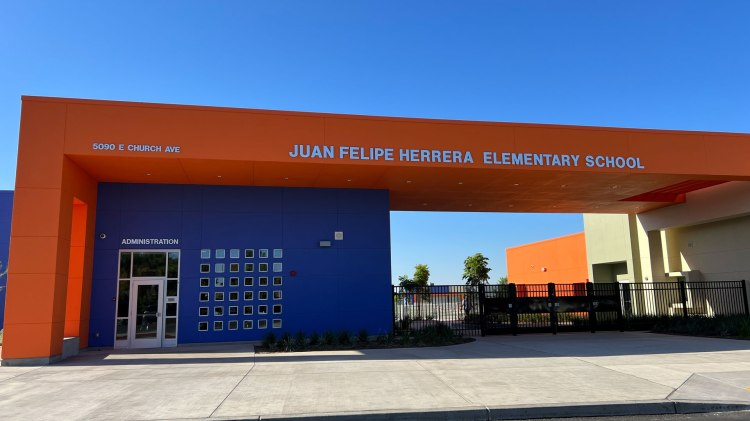 The entrance of Juan Felipe Herrera Elementary School -- a bright orange roof shelter with a deep blue office.