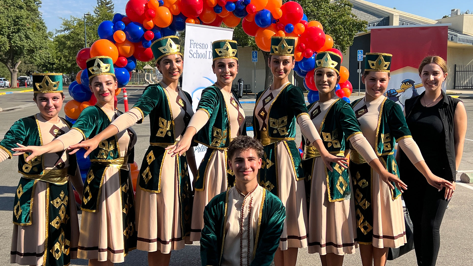 Armenian Dancers pose for a photo in tan and green traditional outfits.