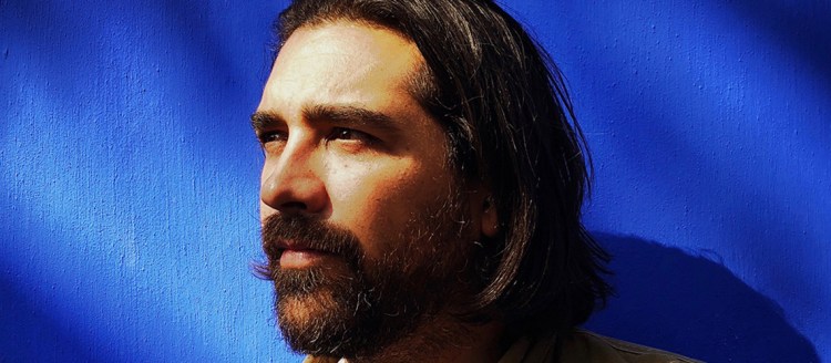 Ryan Christopher Jones headshot in front of a vivid deep blue background.