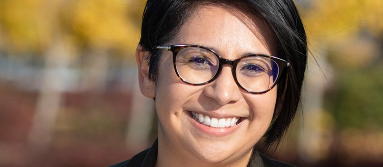 Stephanie Briones headshot in front of an out-of-focus background with fall colors.