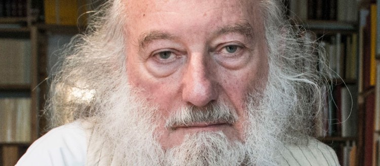 Dr. Claude Mutafian in front of a large book case.