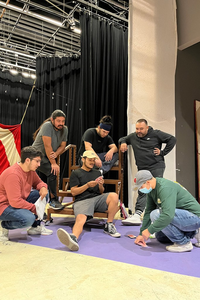 Actors are seen playing cards as a part of rehearsal for Oedipus.