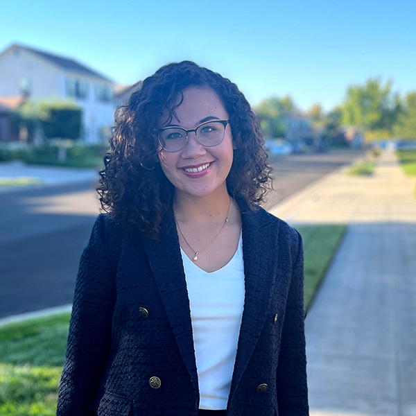 Faith Van Hoven stands on a sidewalk in a residential neighborhood.