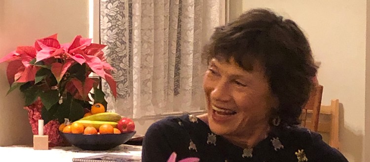 Dr. Toni Wein, a Fresno State professor emerita of English smiles while sitting at her kitchen table.