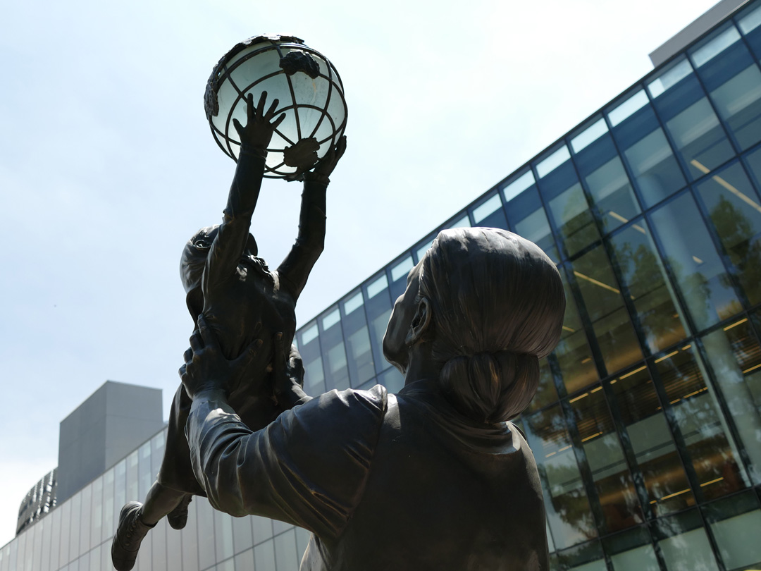 Statue of Jane Addams holding a baby who is holding the globe in the Peace Garden next to the Fresno State Library.