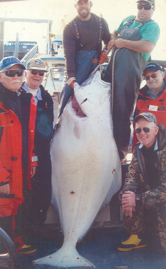 Dr. Arthur Huff and friends in Alaska with a huge fish about the size of most of the men around the fish.