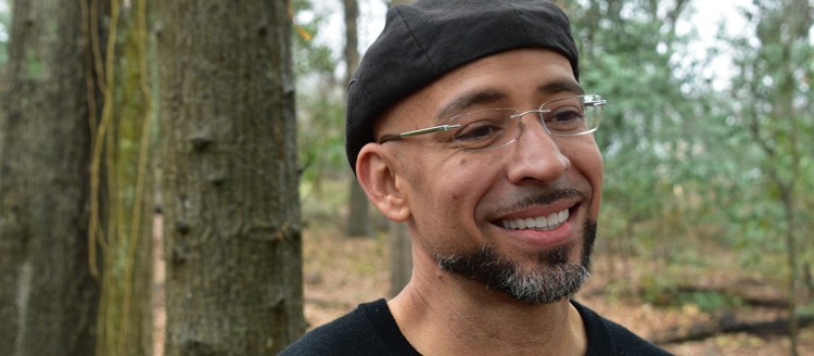 Éric Morales-Franceschini in a black hat and shirt in a forest.