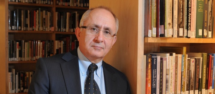 Historian Dr. Taner Akçam in front of book shelves.