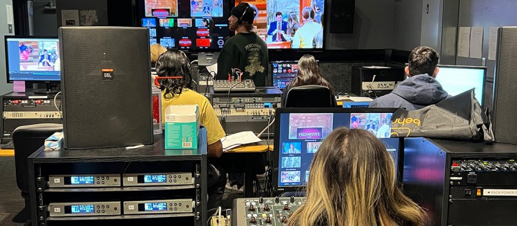 Students in the television studio control room are surrounded by electronics and screens during a Fresno State Focus broadcast.