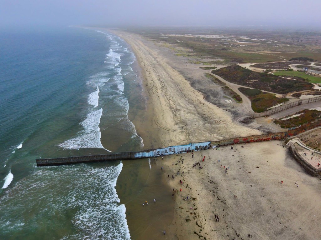 An aerial view of a misty Tijuana beach on the U.S.-Mexico Border with De La Cruz' mural center in the photo.