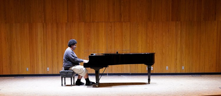 Maurissio rehearses his piece at a piano on stage.