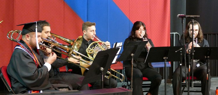 Clendenin Brass Quintet on stage, dressed in black in front of a red and blue backgrop.
