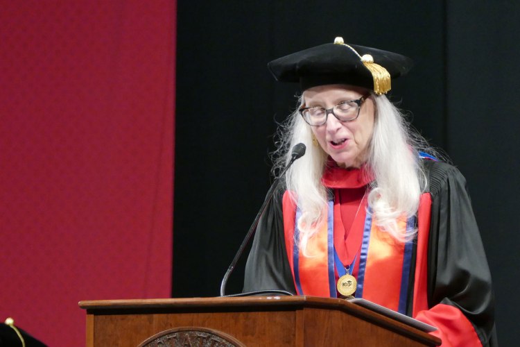 Dean Honora Chapman speaks at the podium in full regalia.