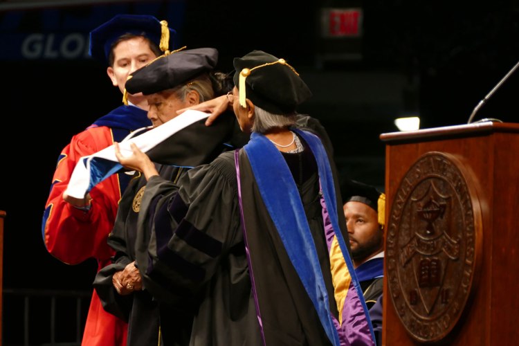 President Saúl Jiménez-Sandoval and Dr. Niken Adisasmito-Smith hood Holly Blossom Wyatt of the Picayune Rancheria of the Chukchansi Indians as her honorary doctorate is awarded.