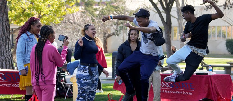 Two students jump while dancing during the African American History Month kickoff event.
