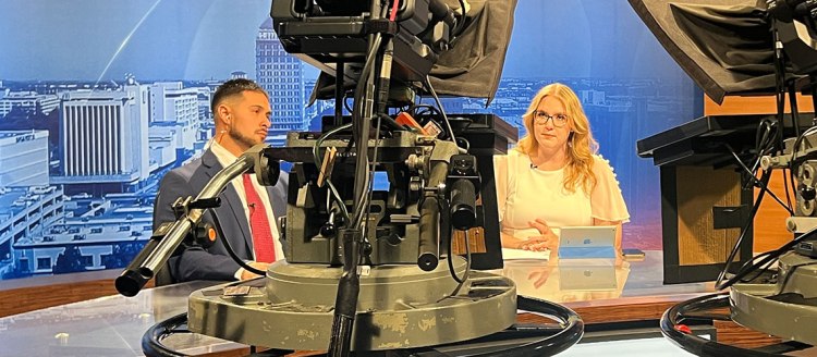 Fresno State Focus student anchors in front of cameras sitting at the news desk.