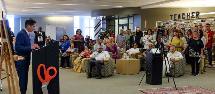 President Saúl Jiménez-Sandoval stands at a podium and speaks to a large crowd of people packed into the 3rd floor of the Fresno State Library.