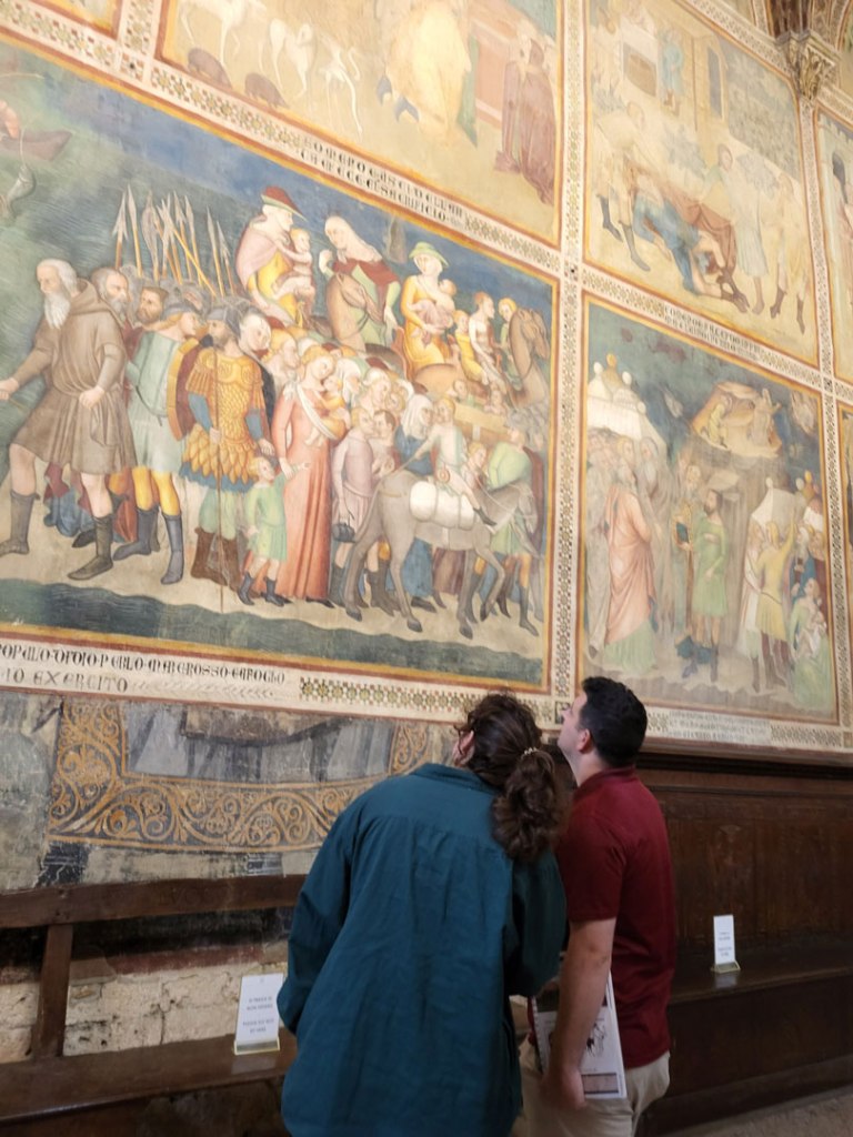 Students look at a depiction of the Israelites crossing the Red Sea -- a wall painting by Bartolo di Fred in the the San Gimignano Collegiate Church of the Assumption of Mary