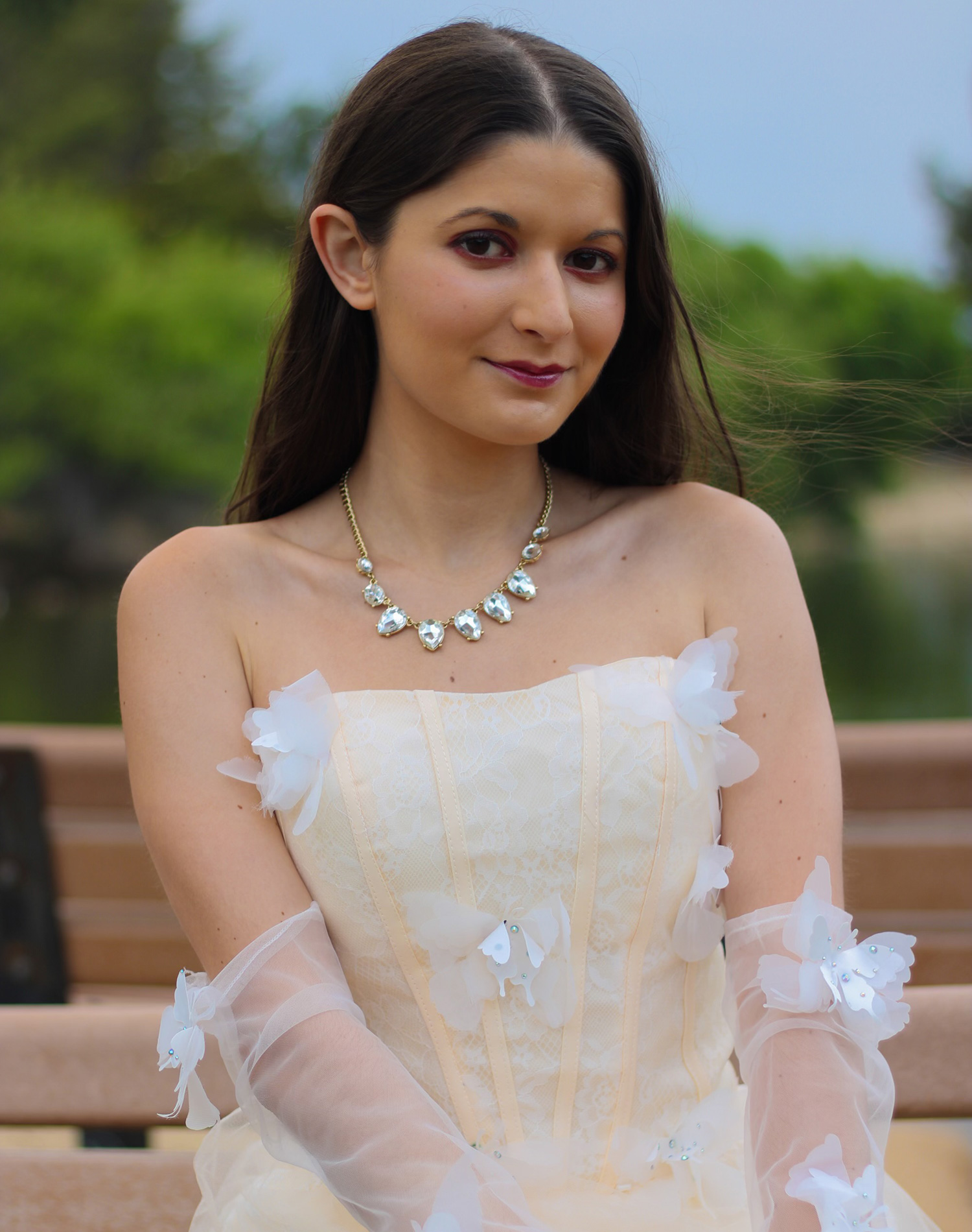 A woman in a white dress with gloves made of white sheer fabric and white fabric butterflies on them.